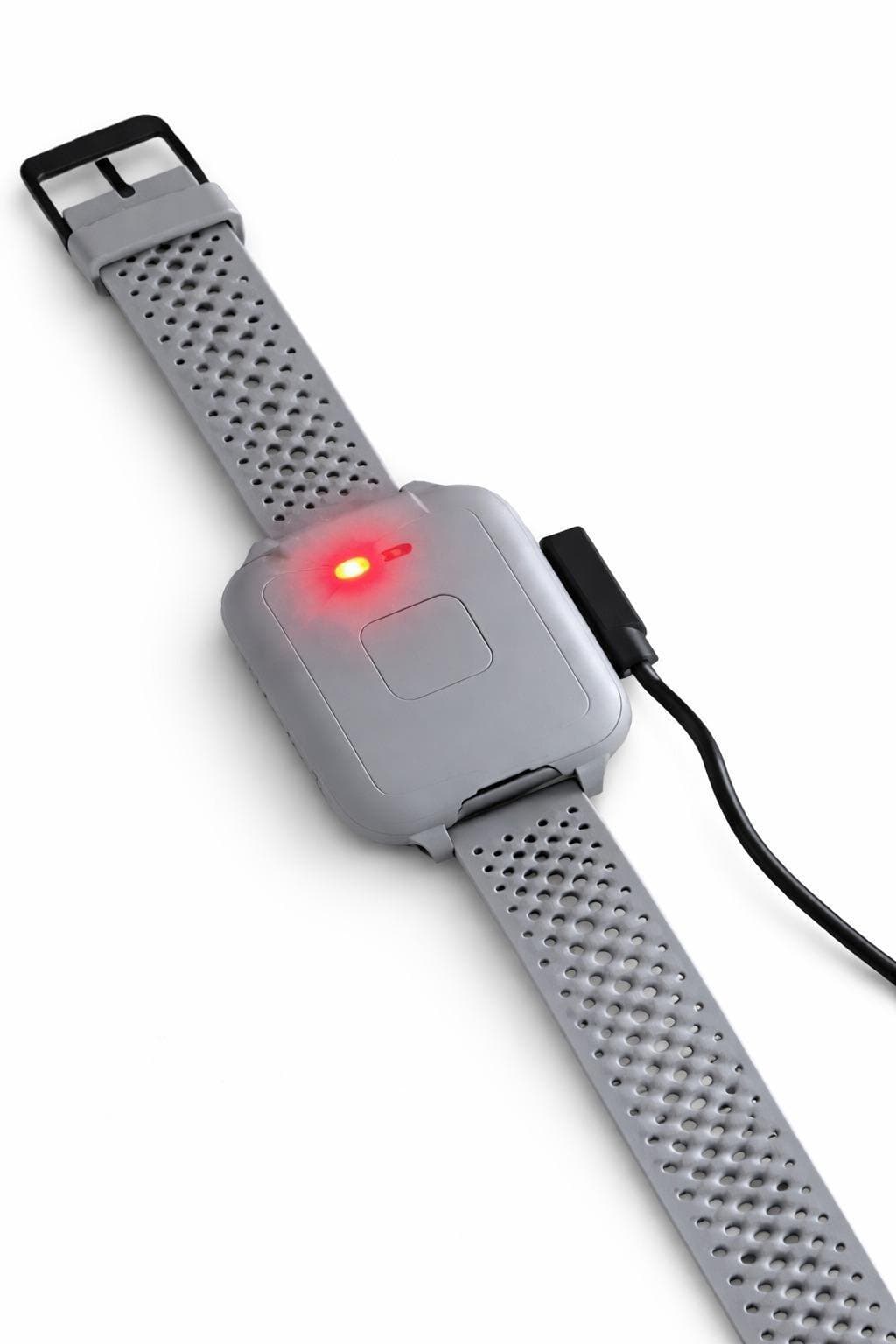 The GCARE bracelet connected to its charging cable, with its indicator light on