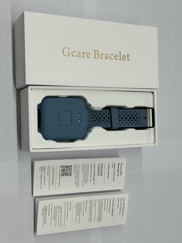 The GCARE bracelet in its open retail box, with the printed quick start leaflet and support and warranty card